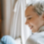 A warm, authentic profile view of a Vata-type woman over 40 smiling gently as she looks off-camera.