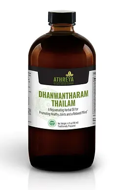 A brown bottle of Dhanwantharam Oil by Athreya Herbs with a green, white, and black label.