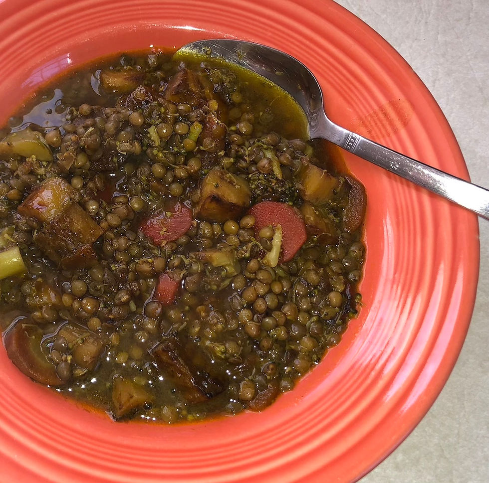 A steaming bowl of lentil soup garnished with fresh ginger and herbs on a rustic tabletop, representing a light and warming Ayurvedic meal.
