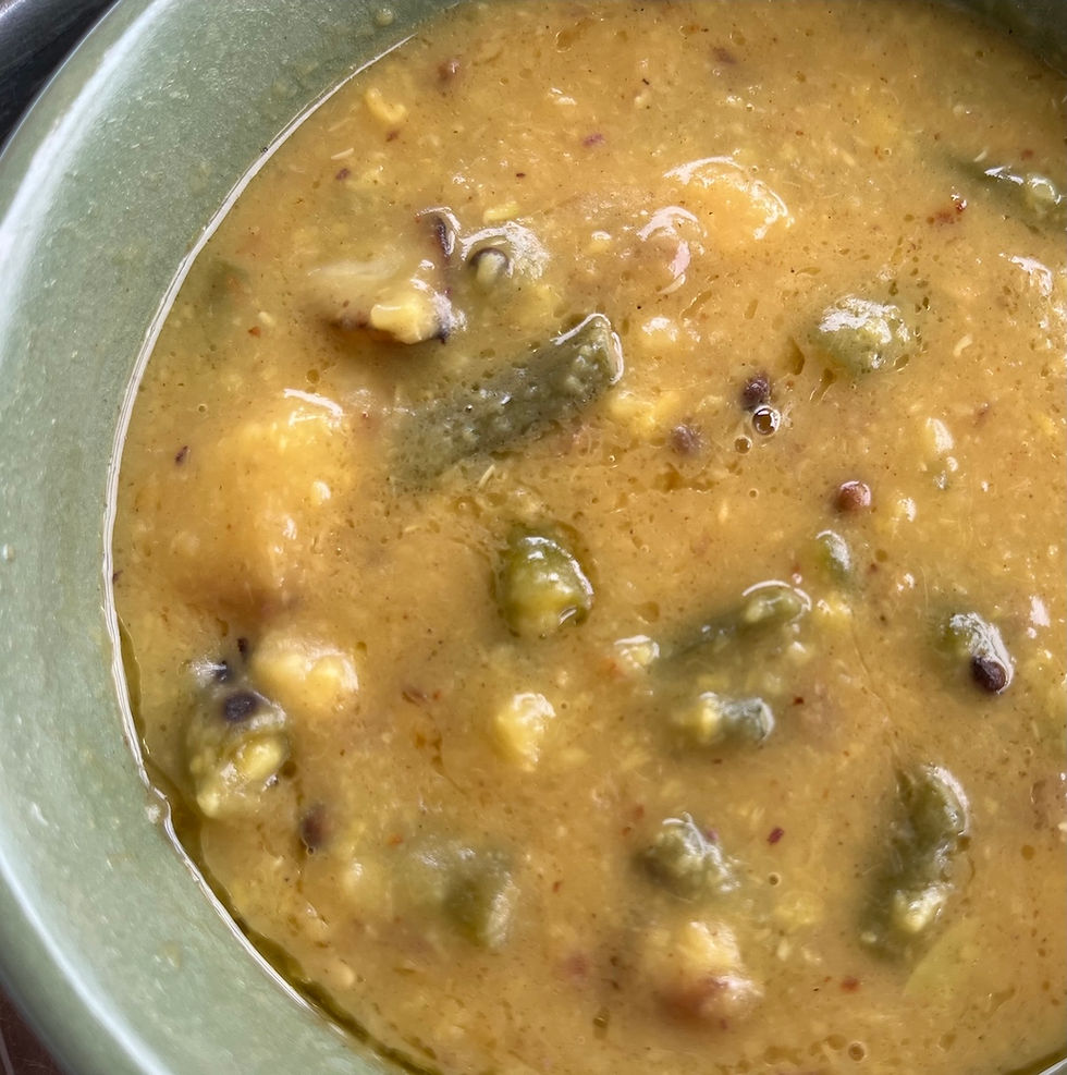 A steaming bowl of yellow mung dhal soup garnished with fresh herbs and spices on a rustic table in Naggar, India.