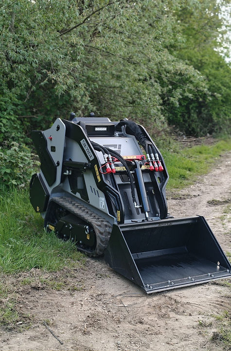 Skidmate SM-780X tracked mini skid steer with standard bucket on a narrow woodland path