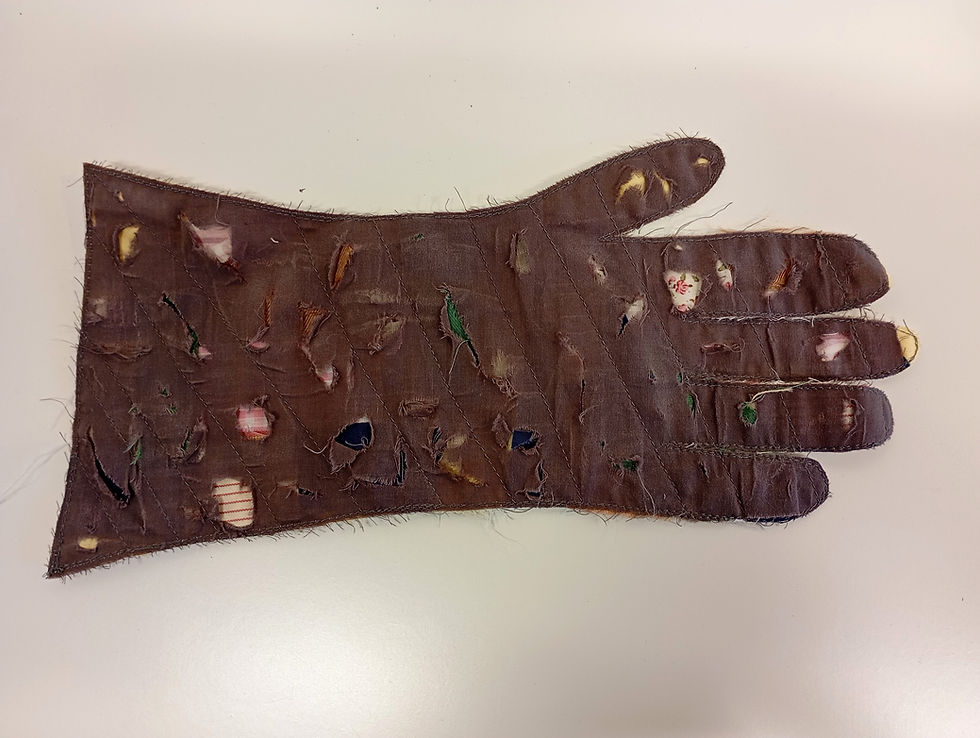 Thumbnail: dark grey fabric cut out from a glove pattern distressed and snippets of other colour fabrics coming through