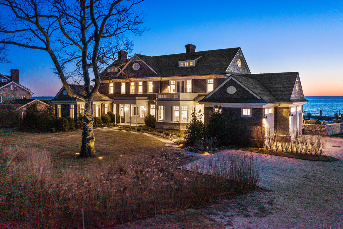 Shingle-style home with landscape lighting at twilight