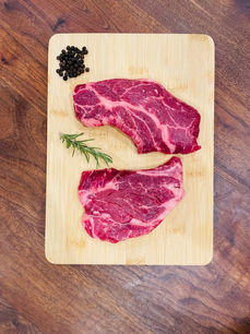 Raw beef brisket on a cutting board with rosemary, knife, salt, and pepper at Weller Beef.