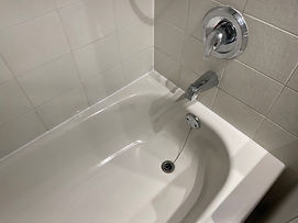 White bathtub with clean caulking along the joints where the tub meets the tiled walls.
