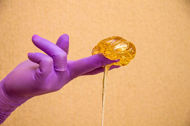Gloved hands with flowing sugar paste for shugaring, depilation.jpg