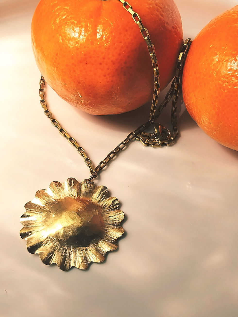 Collier court doré composé d'un médaillon en forme de soleil martelé