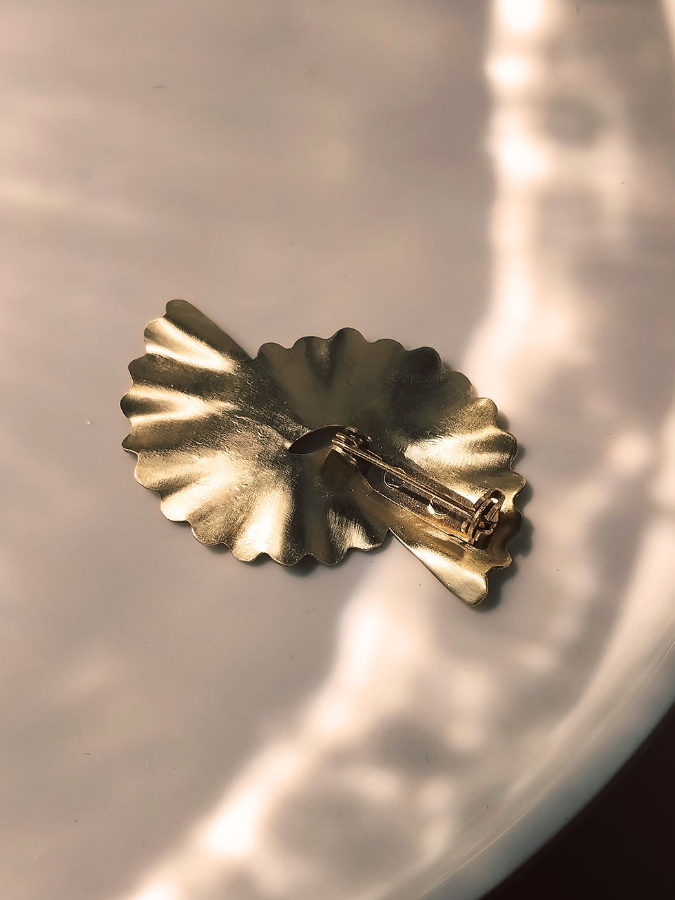 Miniature : Broche dorée surmontée d'une forme dentelée et martelée en rayons.