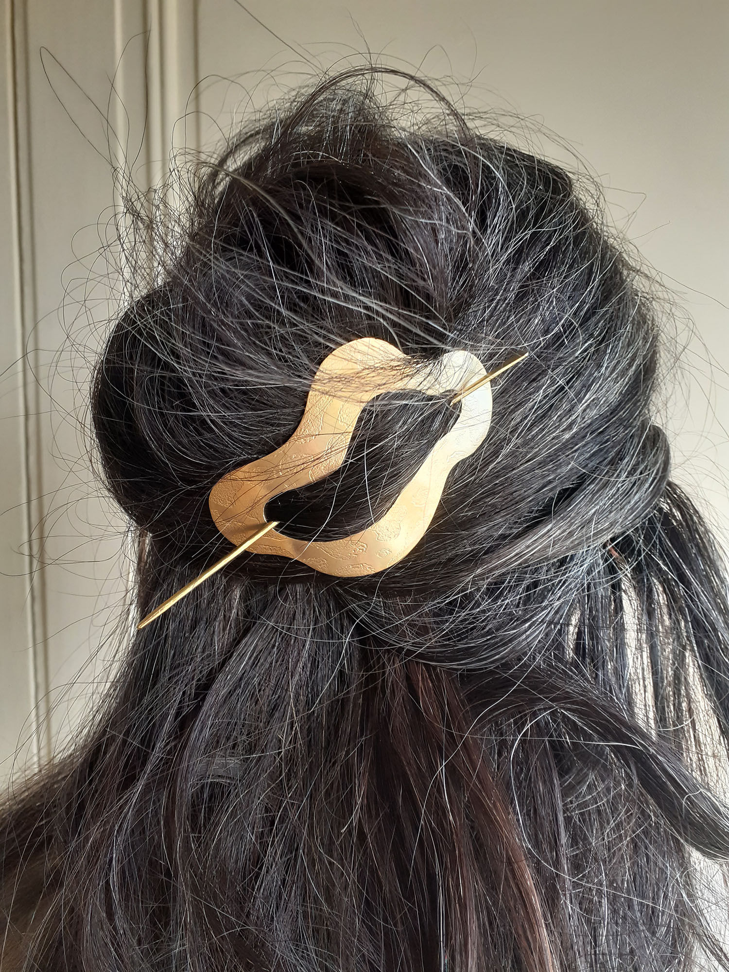 Barette à cheveux dorée et gravée composée d'un pic et et d'une forme souple incurvée.