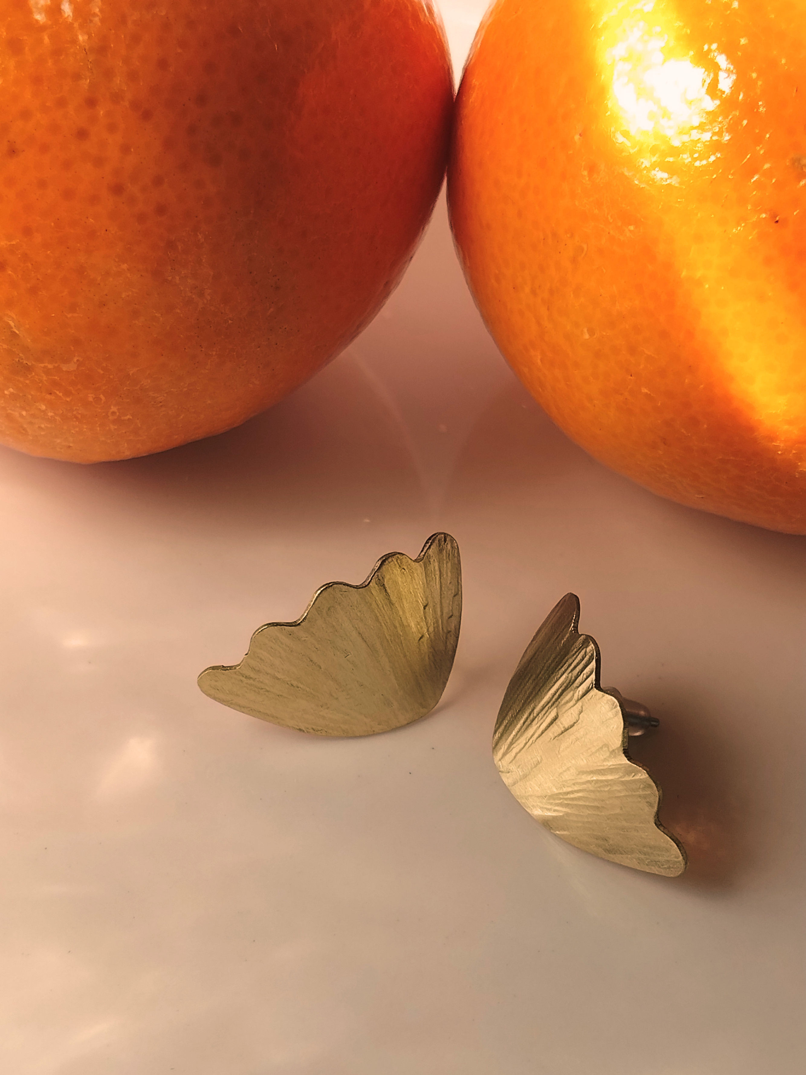 Petites puces d'oreilles dorées en forme d'ailes ondulées et dentelées.