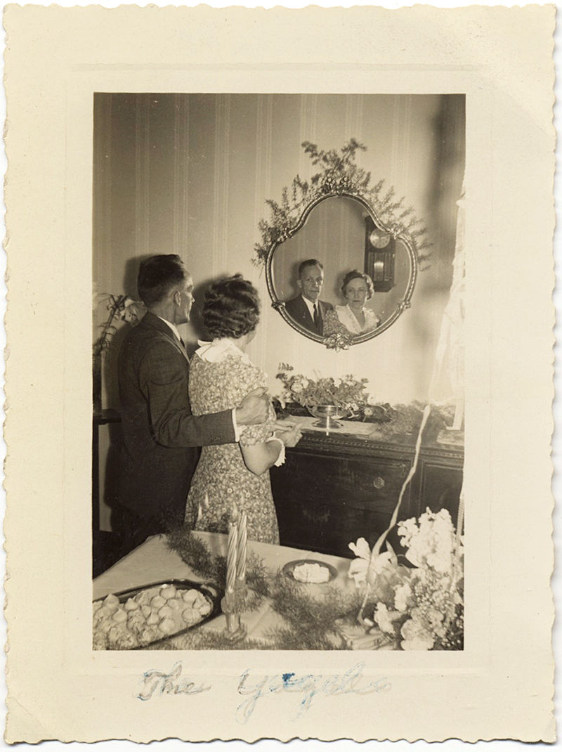 HOMELY COUPLE ADMIRE REFLECTION of SELVES in GILDED ORNATE MIRROR BACK to CAMERA