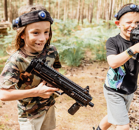 TWO FRIENDS PLAYING LASER TAG IN WOODLAND SETTING