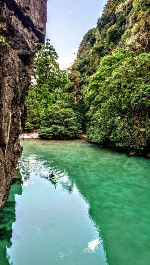 Kayaking in the Philippines: serene, emerald waters between lush green cliffs.