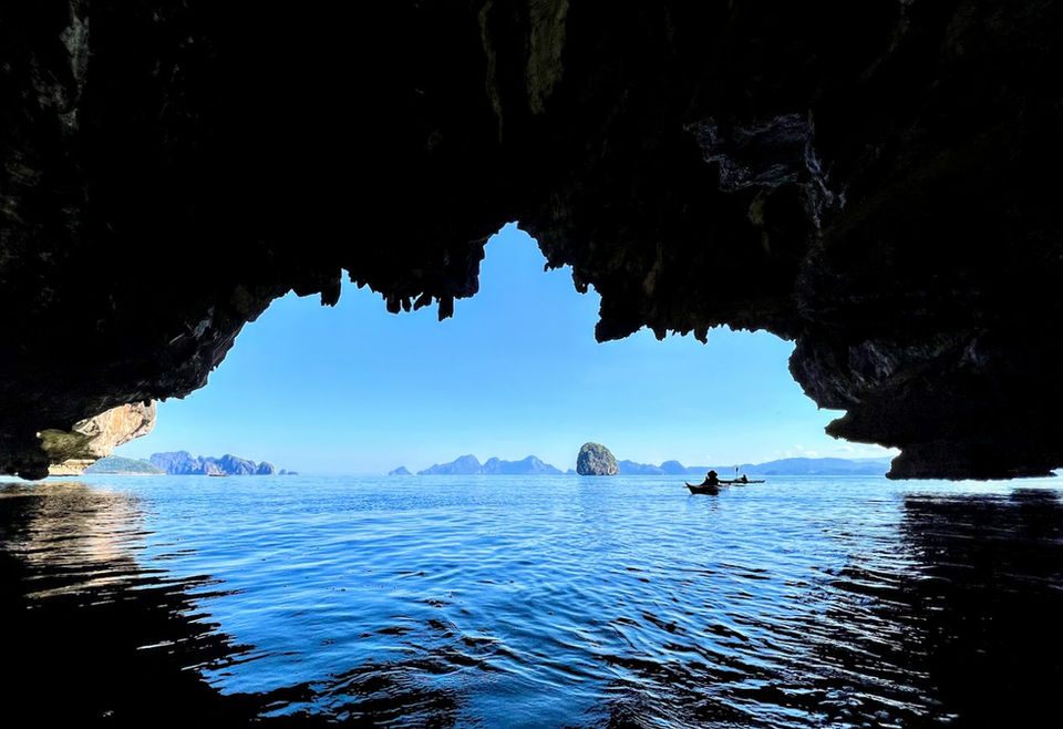 Kayaker paddling towards islands through cave opening