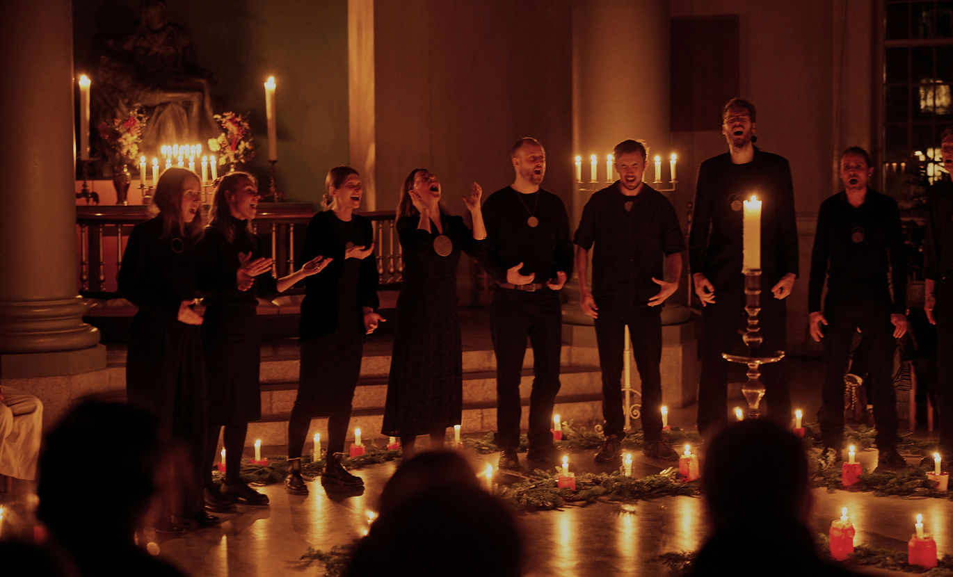 Vokalgruppen NOOR synger a cappella folkesang i levende lys under koncert i kirkerum – ledet af Nini Julia Bang.