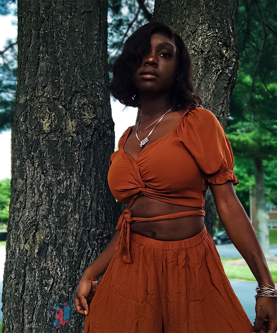 Young woman in orange two-piece outfit by trees