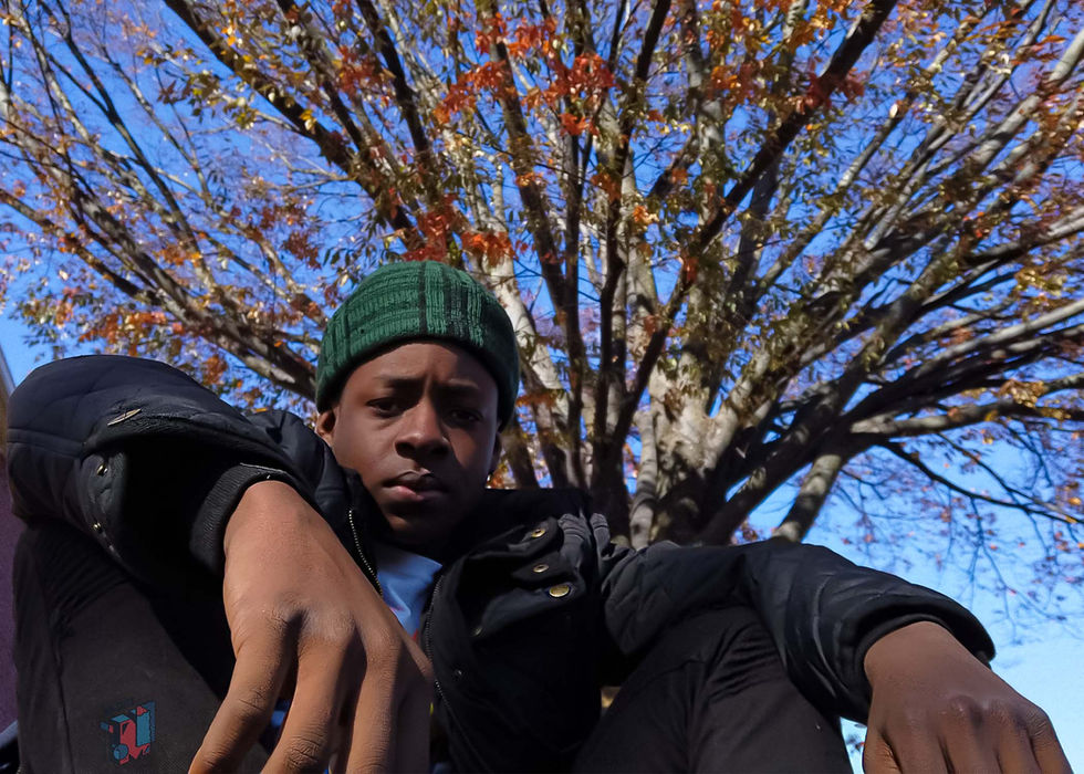 Young man in a beanie under a tree with autumn leaves