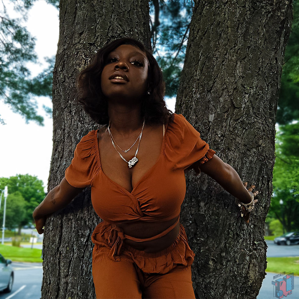 Young woman in orange outfit posing between two tree trunks