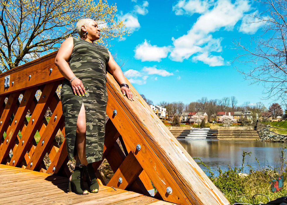 Woman in camouflage dress on wooden bridge by a lake