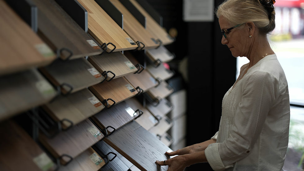 Woman homeowner examining and comparing different flooring samples including hardwood, luxury vinyl plank, and tile options while making renovation decisions for her home