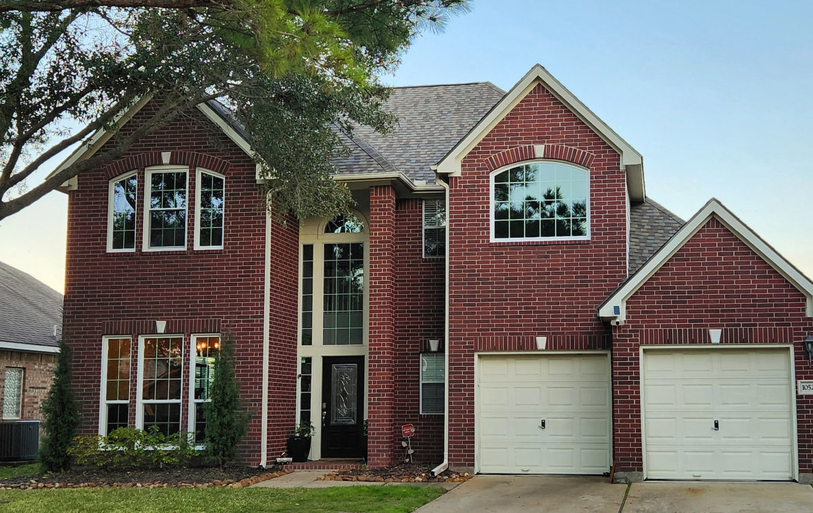 Exterior view of a red brick house with multiple windows and doors.