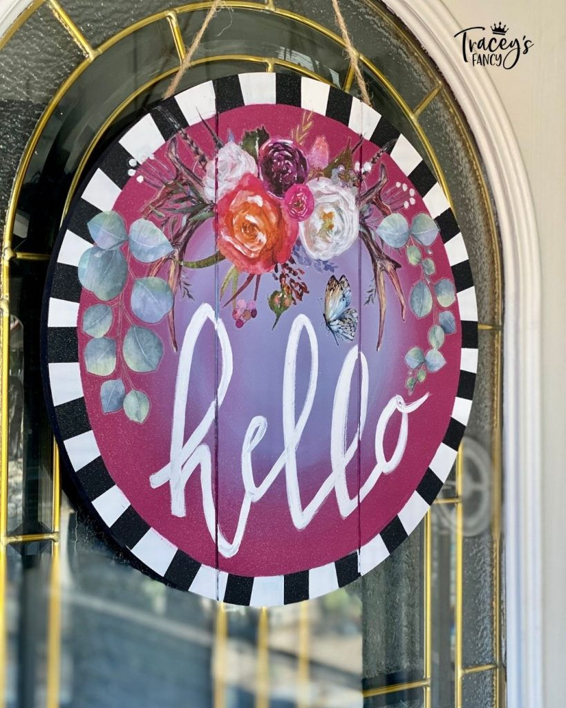 DIY floral boho door hanger design with plum crazy and the gulf blend and a striped border. Hello is written in decorative text by the whimsical artist Tracey's Fancy.