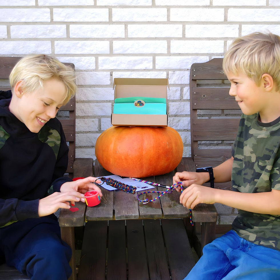 To drenge leger udenfor med FabiBoks Ud i det Blå – den ene maler med fingermaling, mens den anden laver en paracord-nøglerin