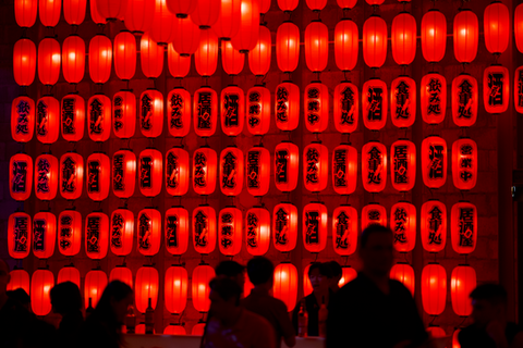 Floor to ceiling wall display of illuminated red Japanese lanterns.