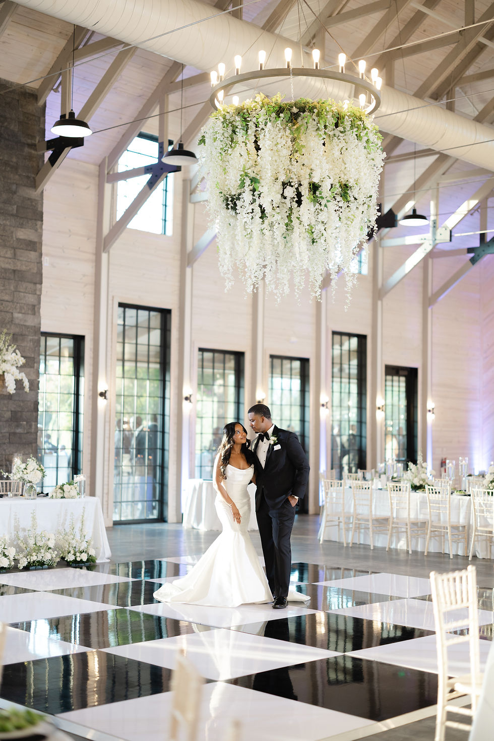 Bride and groom dancing beneath floral chandelier installation