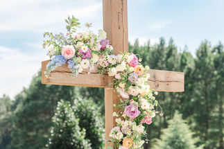 Floral arrangement on cross at outdoor wedding ceremony