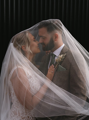 A natural glam bride and her husband on their wedding day posing for a picture under the veil.