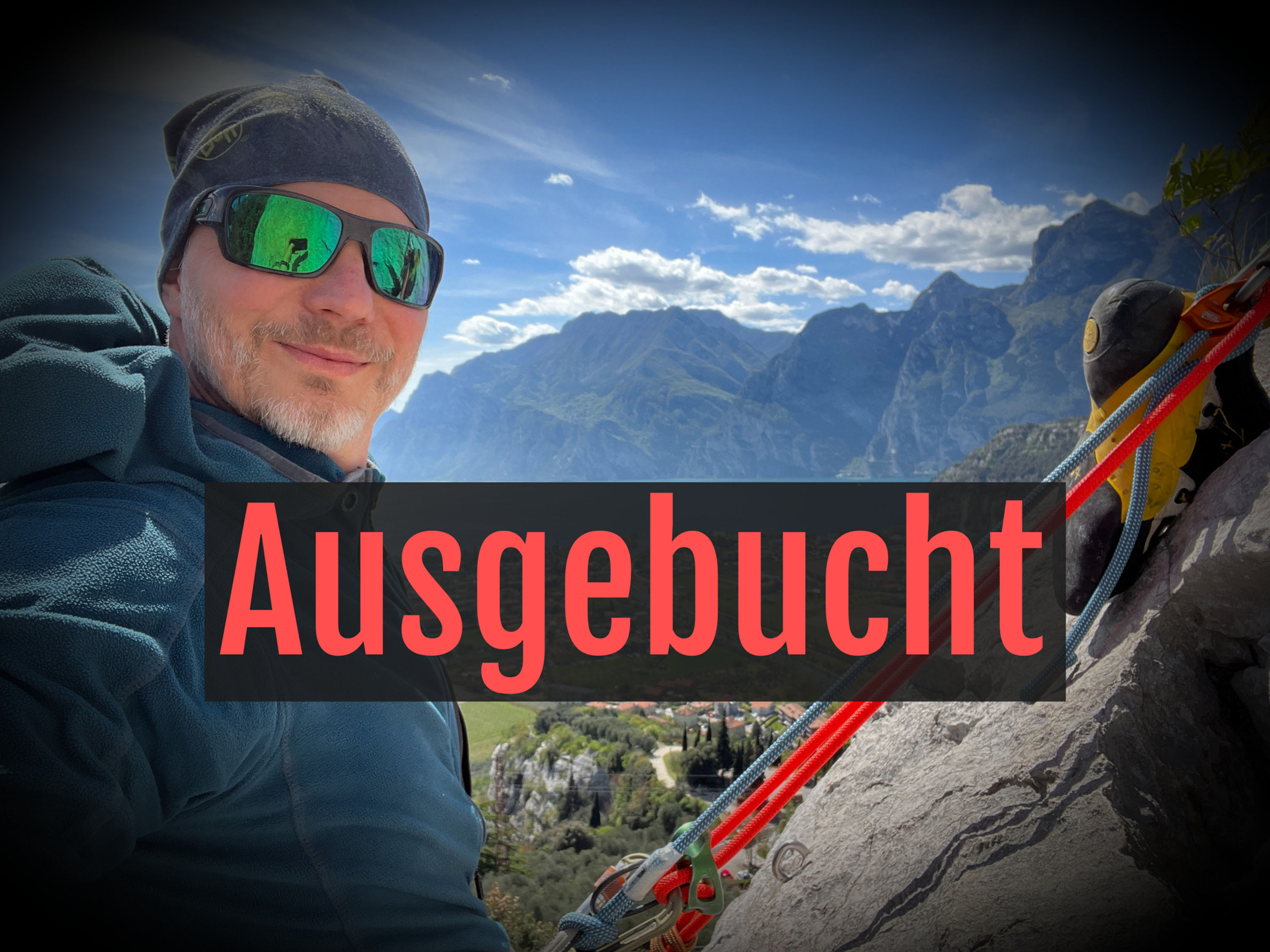 Person hängt in Kletterrute mit Gardasee im Hintergrund 