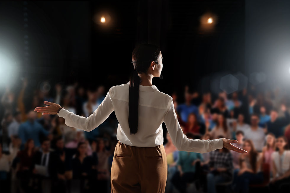 Motivational speaker with headset performing on stage, back view.jpg