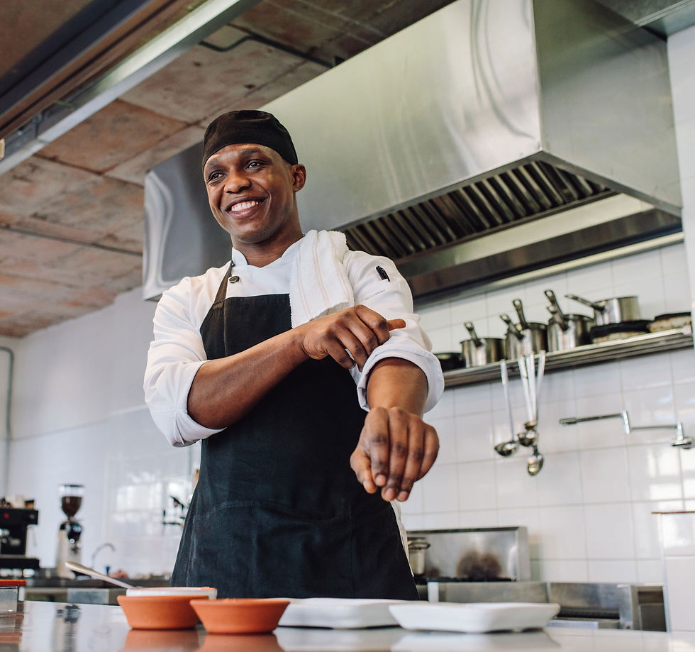 A male chef smiling in a professional kitchen.