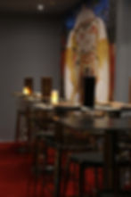 Long bar with stools and candles in front of a colorful mural.