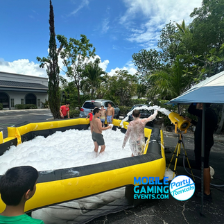 Overhead view of campers playing in thick foam inside yellow inflatable walls, South Florida foam party experience.