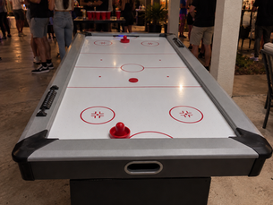 Air hockey table with red paddles set up at an event