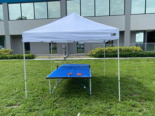 Blue ping pong table beneath a white event tent