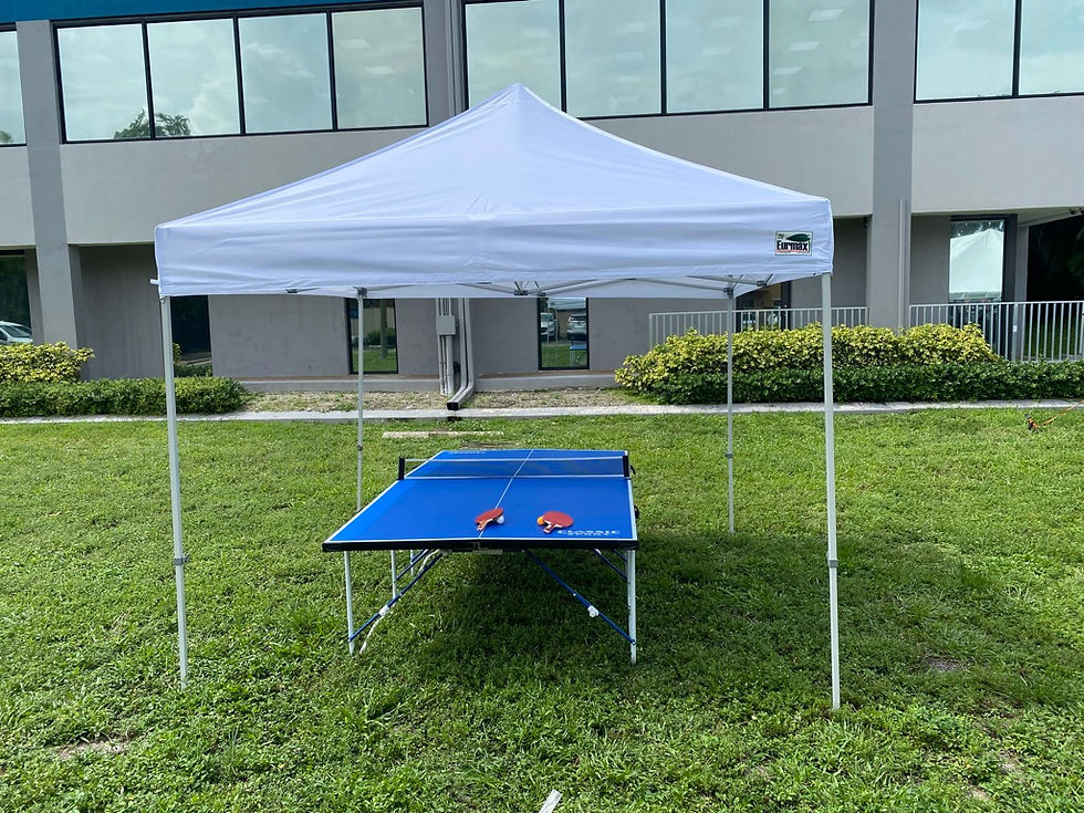 Blue ping pong table beneath a white event tent