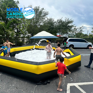 Foam cannon sprays hypoallergenic bubbles while kids jump in an enclosed barrier at a Miami birthday party.