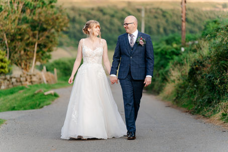 bride and groom walking hand in hand along country road 