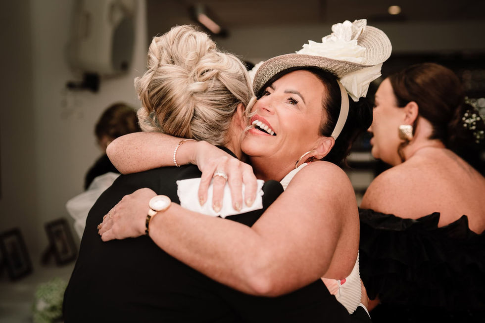 mother of bride cuddling bride after wedding ceremony