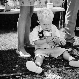 toddler during wedding reception sat on ground at parents feet playing with pebbles