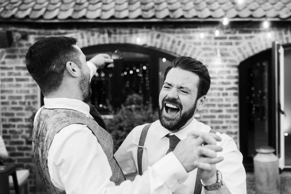 groom and best man dancing together outdoors at howard court wedding venue