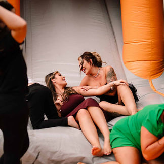wedding guests slumped and laughing on inflatable assault course during wedding reception