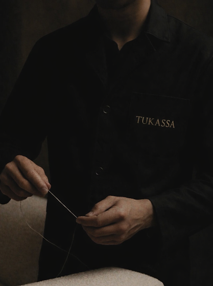 Artisan tapissier travaillant sur un meuble rembourré dans l’atelier TUKASSA.