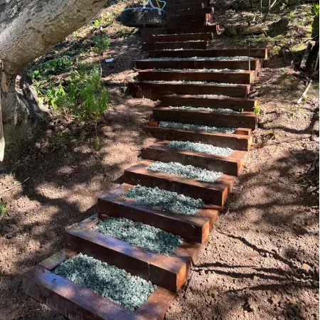 Custom wood landscaping steps with gravel backfill on residential hillside
