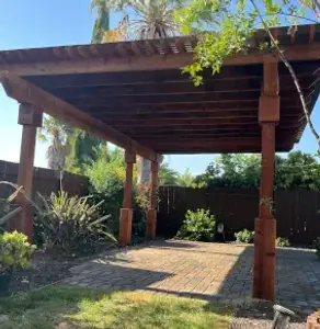 A custom-built wooden pergola patio cover providing shade for an outdoor living space.