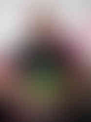 Heavyset trans guy with poster for the event that reads "united power". he also wears a pink feather boa.