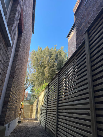 A fence using Jackson fencing Venetian Hit and Miss panels. The fence has horizontal slats and has capping that makes for a premium feel